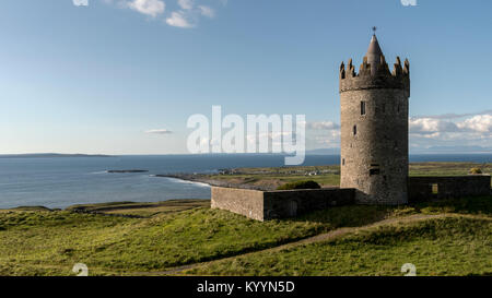 Doonagor Schloss in Irland, die mit Blick auf das Dorf Doolin am Fuß der Klippen von Moher. Die Aran Inseln können Sie in der Ferne gesehen werden. Stockfoto