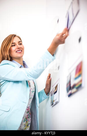 Junge Geschäftsfrau kleben fest an der Wand in der kreativen Büro Stockfoto