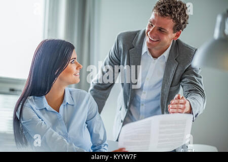 Glückliche junge Unternehmer diskutieren über Dokument in Office Stockfoto