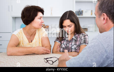 Porträt der jungen Frau sitzen und traurig, während im Gespräch mit älteren Eltern zu Hause Stockfoto
