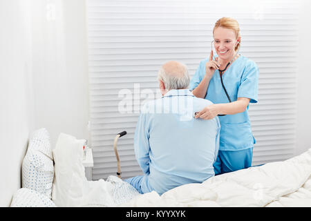 Frau als Arzt untersucht die Atmung eines kranken Senior mit dem Stethoskop Stockfoto