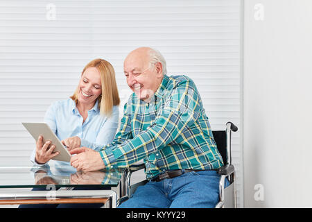 Junge Frau, die als Tochter mit Senior als Vater Spaß haben mit einem Tablet-PC Stockfoto