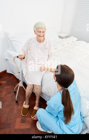 Junge Pflegehilfe unterstützt und kümmert sich um behinderte alte Patienten in Pflegeheimen Stockfoto