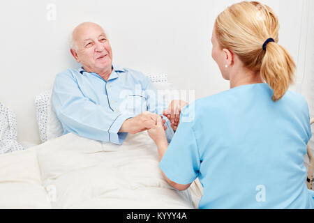 Krankenschwester hält die Hände eines Senior als Patient im Krankenhaus Stockfoto