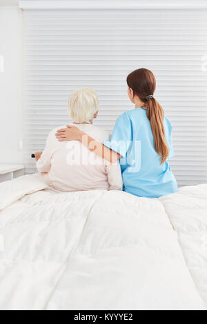 Fürsorgliche Betreuer sorgt für ältere ältere Frau und gibt ihr Komfort Stockfoto
