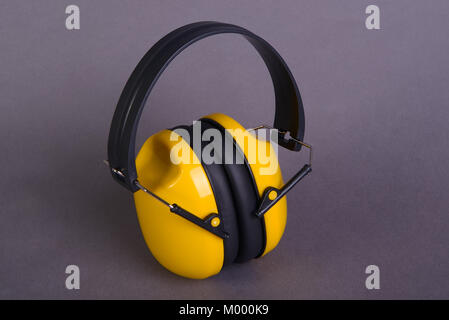 Gelbe Gehörschützer auf grauem Hintergrund Stockfoto