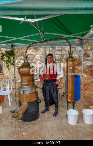 Arsos Dorf, Zypern - 8. Oktober 2017: Der Mann, der in den traditionellen Cyprian Kleid posiert mit seinem noch für zivania. Stockfoto