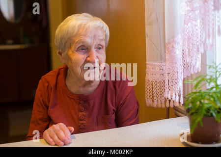 Eine ältere Frau, die am Tisch sitzen. Stockfoto