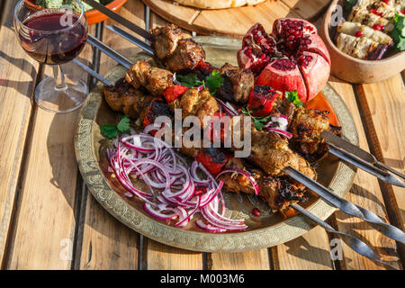 Fleisch Shish Kebab auf einem Teller mit Zwiebeln, Granatapfel Samen, Pfeffer, Holz- Hintergrund. Stockfoto