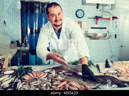Verkäufer zeigt Hände Fisch auf Zähler im Supermarkt Stockfoto