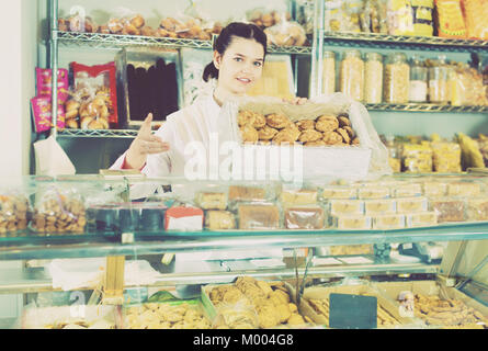 Junge freundlich lächelnde Frau Verkauf von Cookies und anderen Füllungen Stockfoto