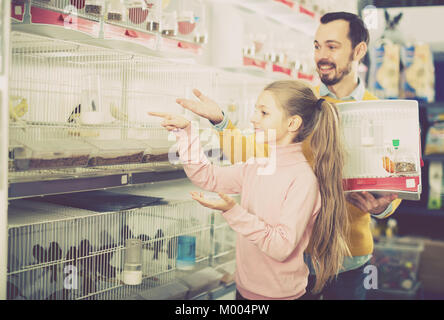 Der Mann mit dem Mädchen in Anbetracht der verschiedenen Arten von Vögeln in einem Pet Shop Stockfoto