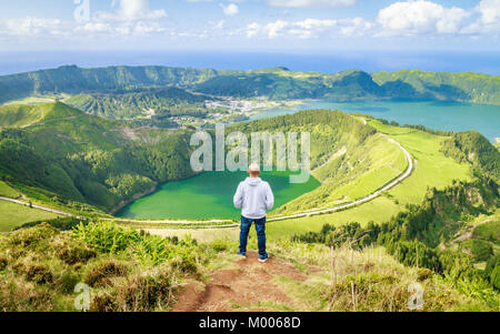 Junger Mann genießen Sie den atemberaubenden Blick von Sete Cidades Seen vom Aussichtspunkt Miradouro Boca do Inferno, Sao Miguel, Azoren, Portugal Stockfoto