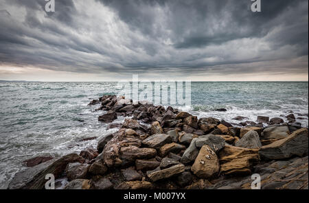 Wellen der Adria Absturz über eine künstliche Felsen unter stürmischen Himmel. Stockfoto