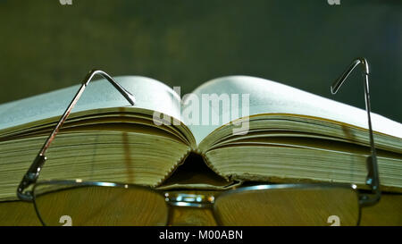 Offene Bibel mit Brille auf die alte Tabelle. Stockfoto