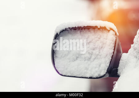 Das Auto ist mit Schnee bedeckt. Schnee am Rückspiegel. Konzept der im Winter fahren mit Schnee auf der Straße. Getönten Foto mit kopieren. Stockfoto