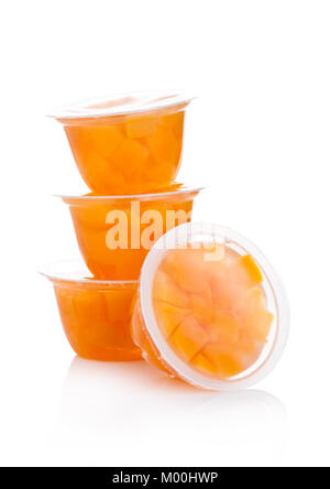 Einzelne Tassen mit Pfirsich in der Grütze auf weißem Hintergrund Stockfoto