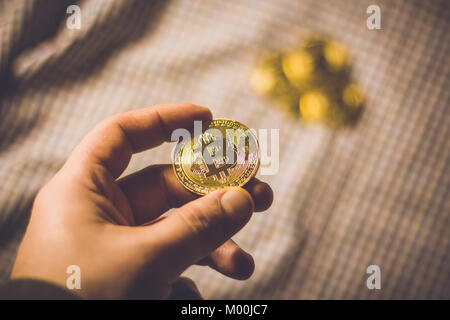 Mann hand Bitcoin Münze mit ein paar goldenen Münzen im Hintergrund Stockfoto