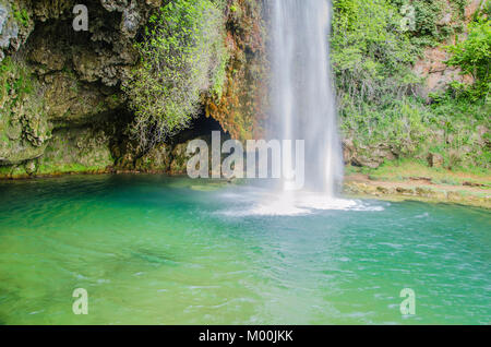 Höhle mit Wände mit bunten Moosen mit Wasserfall als Tür im französischen Dorf Salles La Source besiedelten Stockfoto