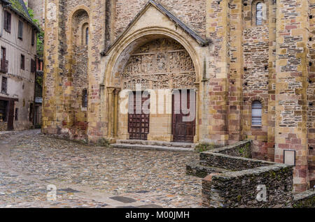 Hauptfassade der Abtei von Saint Foy im mittelalterlichen Dorf Conques, in der französischen Region Okzitanien, ist ein regelmäßiger Anschlag für die Pilger, die ma Stockfoto