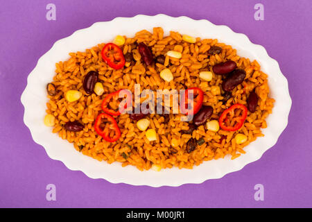 Mexikanischen Stil pikanter Reis mit Bohnen und rote Chilis gegen einen violetten Hintergrund Stockfoto
