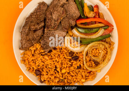 Mexikanischen Stil Steak Fajitas mit würzigen Reis und Paprika gegen einen orangen Hintergrund Stockfoto