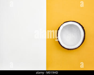 Coconut Flach halben Kokosnuss in der Schale liegt auf zwei-ton Hintergrund Draufsicht trendigen bunten Foto mockup mit Platz für Text Stockfoto