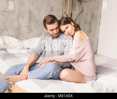 Liebespaar. Hübscher junger Hipster mit Bart und attraktive Frau zu Hause ausruhen, während auf dem Bett, zu Hause zu sitzen. Stockfoto