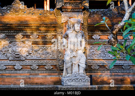 Steinmetzarbeiten und die Statue an der Außenwand eines balinesischen Compound in Ubud, Bali, Indonesien. Stockfoto