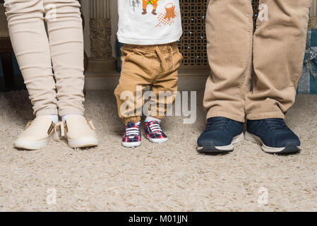 Beine von einem Ehepaar mit einem Kind in den Schuhen Stockfoto