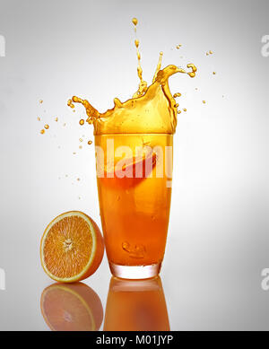 Orangensaft splash in Glas mit orange Schnitt Stockfoto