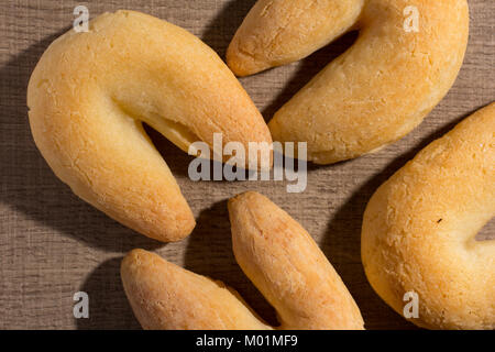 Käse Brot Brötchen als Chipa in Brasilien bekannt, geformt wie ein Hufeisen. Traditionelle Nachmittag Mittagessen. Snacks auf Holz Tisch, flaches Design legen. Stockfoto