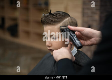 Kleiner Junge auf einem Haarschnitt im Friseur sitzt auf einem Stuhl. Stockfoto