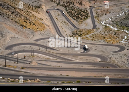 Autos und Lastwagen fahren auf der Drehen und Drehen gewundener Straße durch hohen Anden in Chile, Südamerika Stockfoto