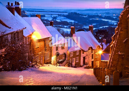 Gold Hill Shaftesbury Dorset, nach einem Rückgang von Schnee und beleuchtet von einem Sonnenuntergang am Abend an einem kalten Januar winter Abend Stockfoto