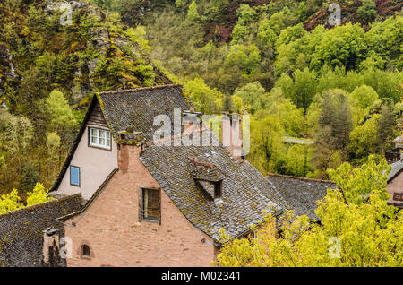 Die baumkronen und die Dächer der Häuser am Rande des Dorfes von Conques sind in die Schönheit der Landschaft verwirrt Stockfoto