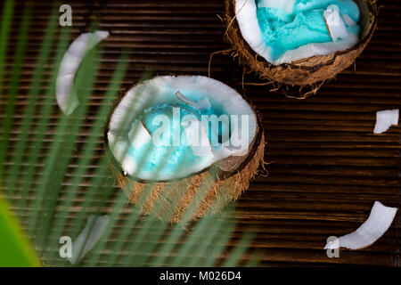 Blue Ice Cream Coconut Schüssel. Schüssel mit Eis in Hälften der Mutter auf Blatt Hintergrund Stockfoto