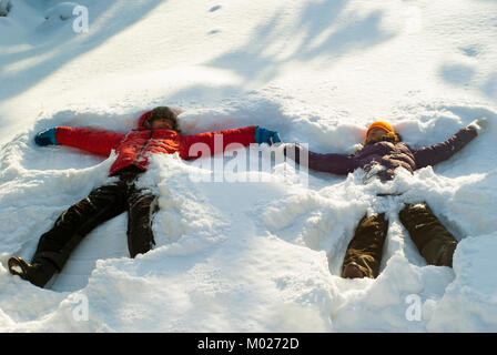 Zwei Menschen, ein Mann und eine Frau, stellen jetzt Angels' in eine tiefe Schneeverwehungen, halten sich an den Händen Stockfoto