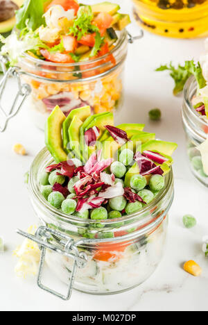 Frische Salate in Glas mit frischem Gemüse und gesunde Dressings, auf weissem Marmortisch, kopieren Raum Stockfoto