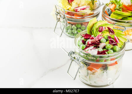 Frische Salate in Glas mit frischem Gemüse und gesunde Dressings, auf weissem Marmortisch, kopieren Raum Stockfoto