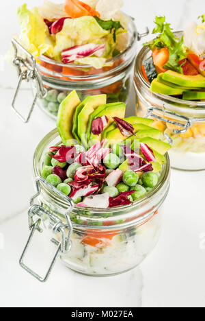 Frische Salate in Glas mit frischem Gemüse und gesunde Dressings, auf weissem Marmortisch, kopieren Raum Stockfoto