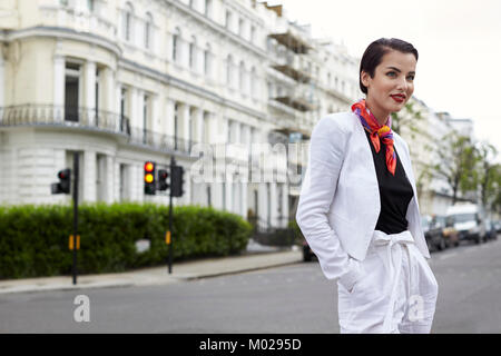 Lächelnde Frau, die in der Straße tragen weiße Bettwäsche Anzug Stockfoto