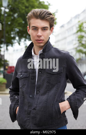 Junger Mann in Schwarz Denim Jacke mit Händen in den Taschen Stockfoto