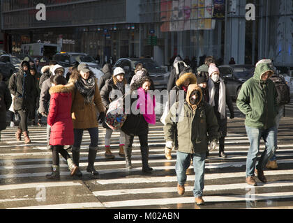 Menschen an einem kalten Wintertag Überschreiten der 6. Avenue an der 42. Straße am Bryant Park gebündelt, in Midtown Manhattan. Stockfoto