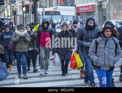 Menschen an einem kalten Wintertag kreuz Broadway an der 34th Street in der Nähe von Macy's in Manhattan gebündelt. Stockfoto