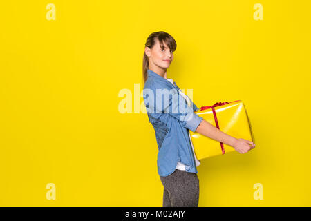 Glückliche junge Frau, die ein gelber Geschenkbox Stockfoto