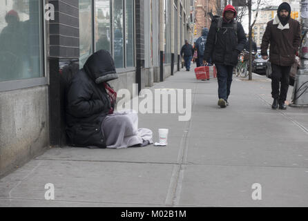 Obdachloser sitzt auf dem Bürgersteig um Geld bittet in Midtown Manhattan. Stockfoto