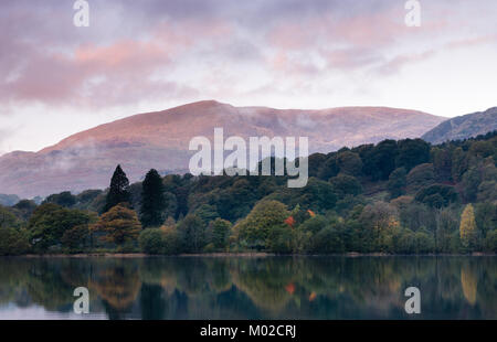 Ein ruhiger, noch morgen am Coniston Water im Lake District mit frühen Morgen Licht auf dem Hügel in Richtung der Alte Mann von Coniston. Stockfoto