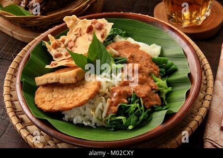 Nasi Pecel, die traditionellen javanischen Reisgericht aus gedämpftem Reis mit Gemüse Salat, Dressing, Tempeh, Tofu, und Cracker Stockfoto