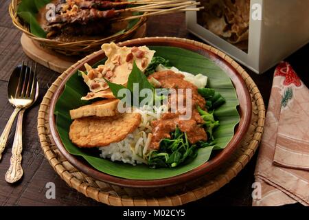 Nasi Pecel, die traditionellen javanischen Reisgericht aus gedämpftem Reis mit Gemüse Salat, Dressing, Tempeh, Tofu, und Cracker Stockfoto